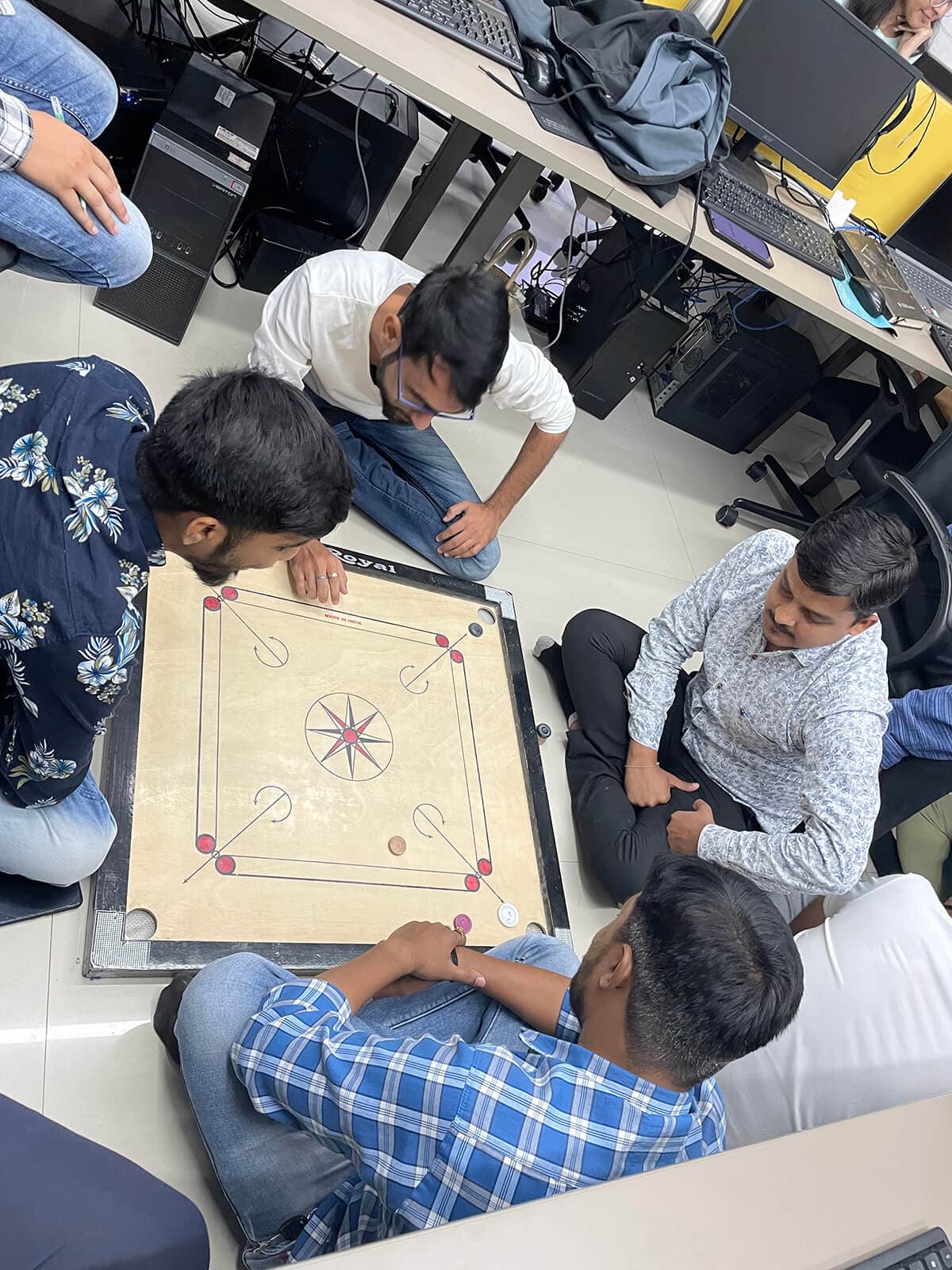 Engross colleagues playing carrom together in the office